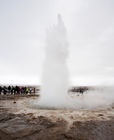 Geysir erupting with spectators close-by